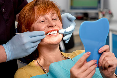 A woman receiving dental care with a smiling expression, surrounded by dental professionals.